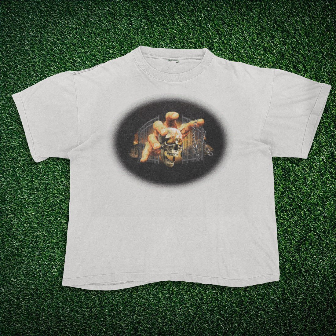 White tee with a glowing skull and chained hand graphic